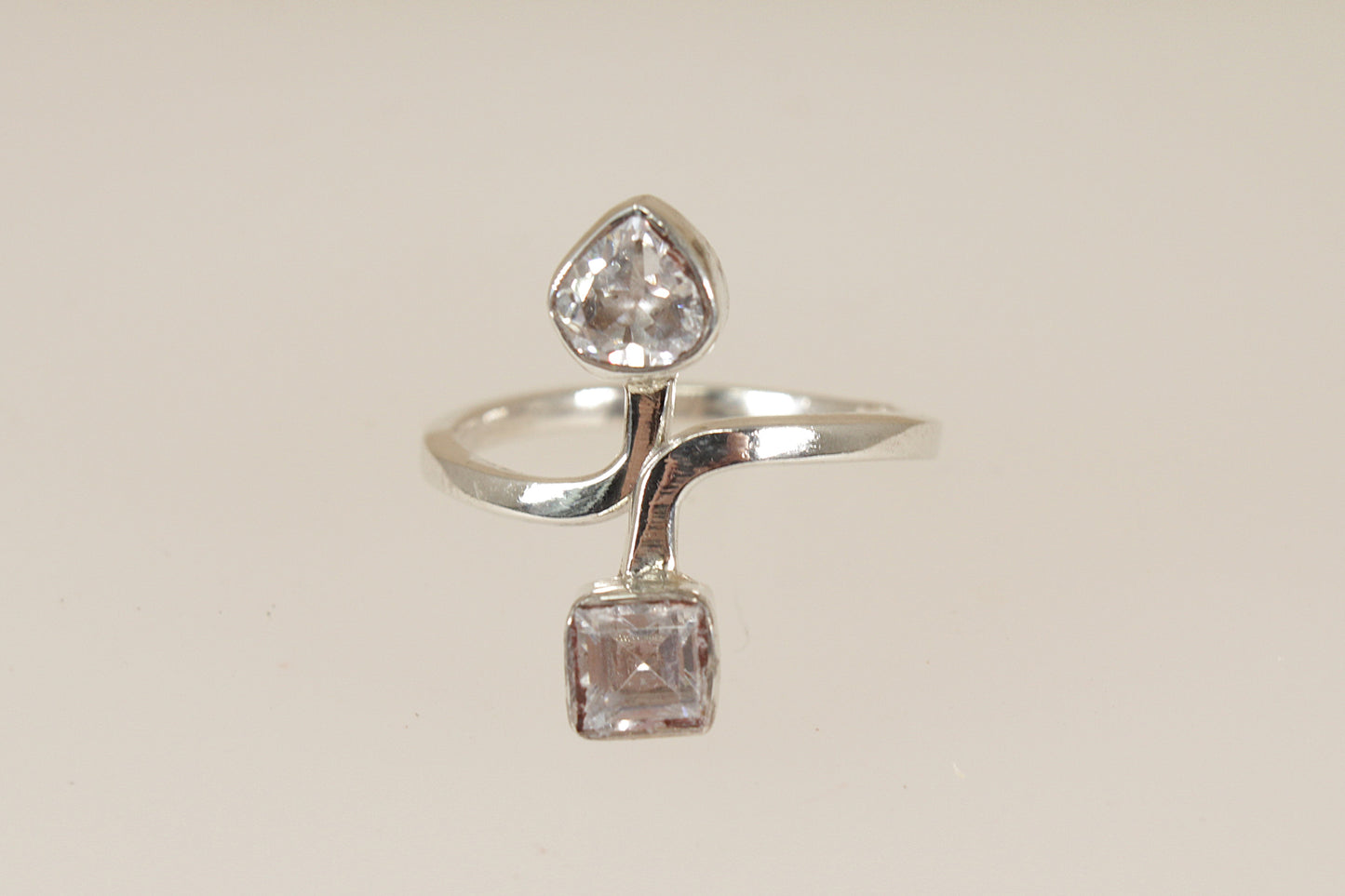 Silver ring with two cz cubic zirconia diamond simulant gemstones on a beige background