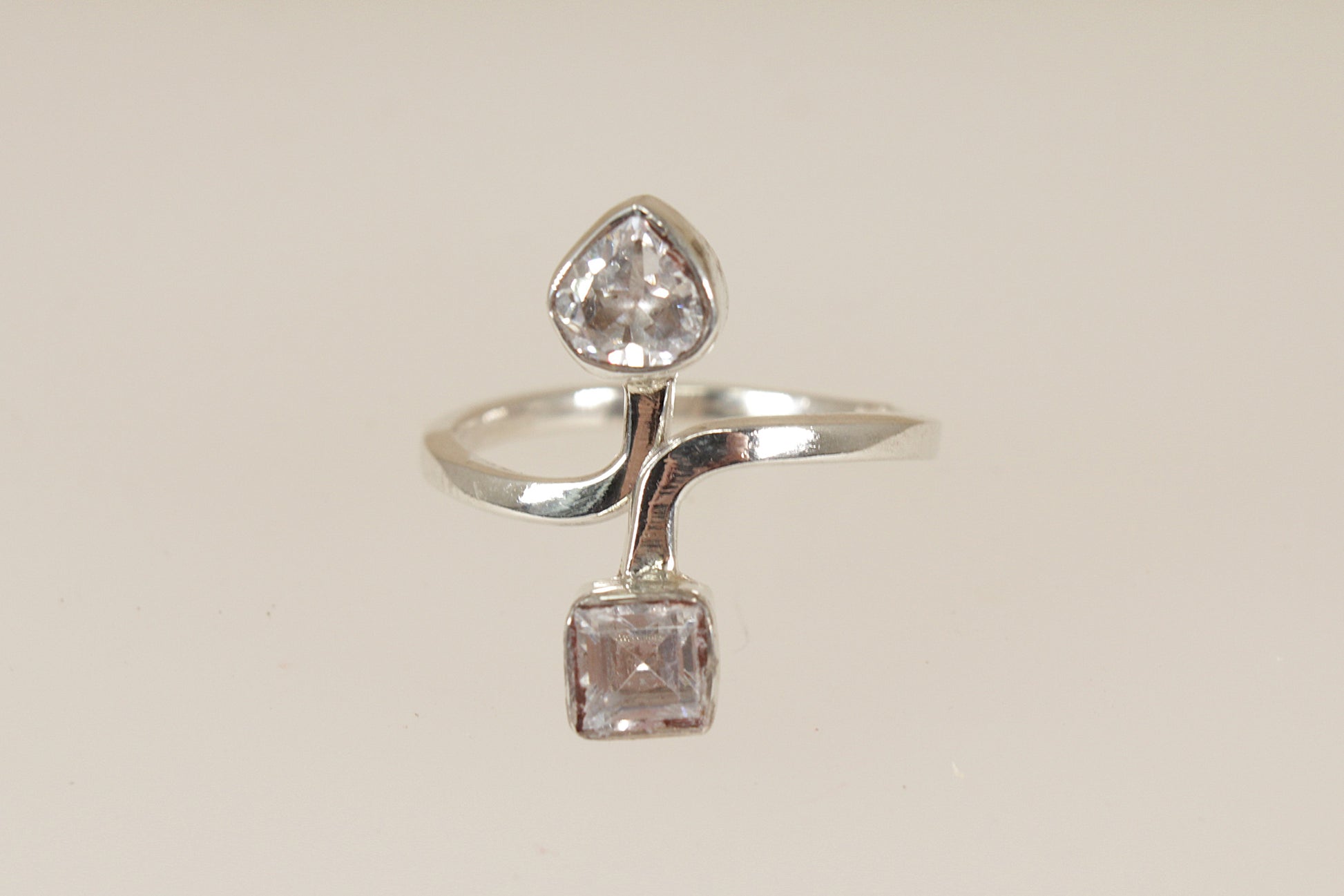 Silver ring with two cz cubic zirconia diamond simulant gemstones on a beige background