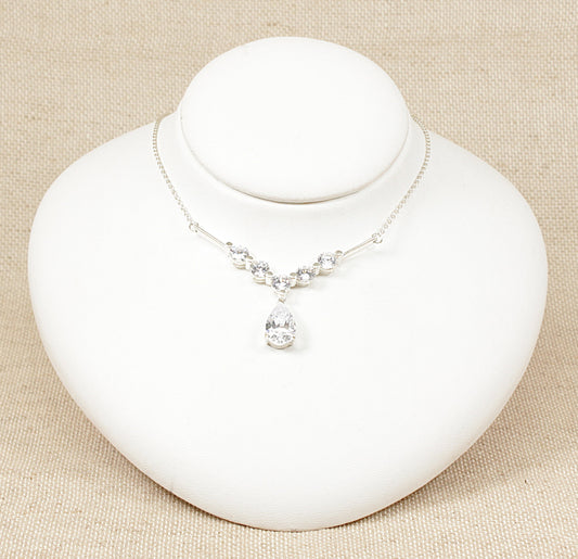 This silver necklet features an elegant arrangement of cubic zirconia gemstones, creating a sparkling and sophisticated look. The design includes five round CZ stones set along a V-shaped mount, which adds a graceful contour to the necklace. The V shape not only accentuates the neckline but also gives a modern and refined touch to the piece. The necklet is in excellent condition and stamped 925 for sterling silver.