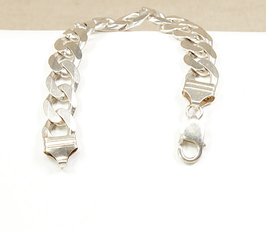 A sterling silver flat curb link bracelet displayed on a black surface.