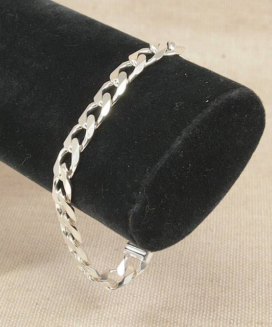 Silver curb link chain bracelet on a black velvet stand with a beige background