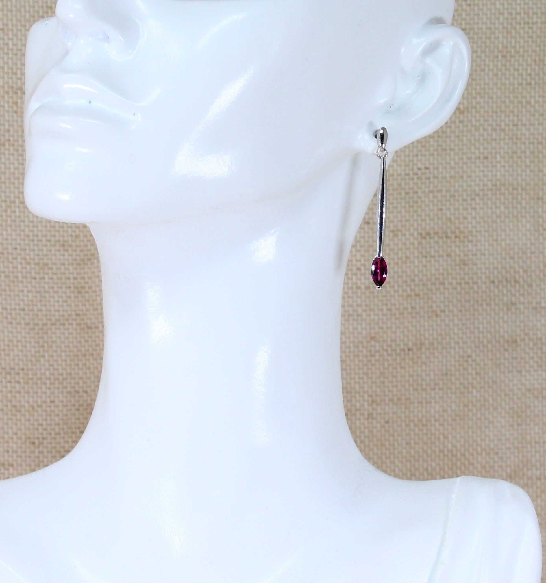 A pair of silver drop earrings with marquise cut cubic zirconia gemstones on a mannequin head.