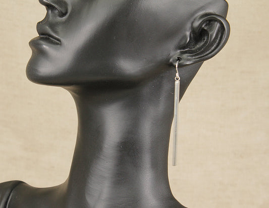 A sleek and timeless pair of sterling silver drop earrings, featuring a minimalist 2 inch long polished bar that elegantly elongates the neckline. Their simple yet sophisticated design makes them a versatile accessory. They have a secure hook fastening and are stamped 925 for sterling silver.