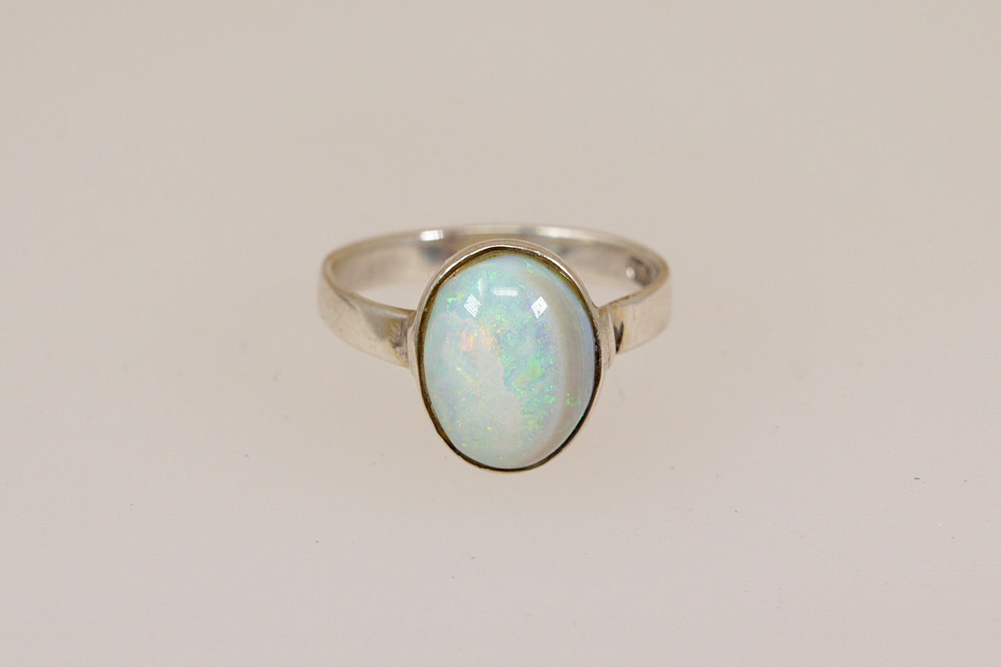 Silver ring with an opal stone on a light beige background
