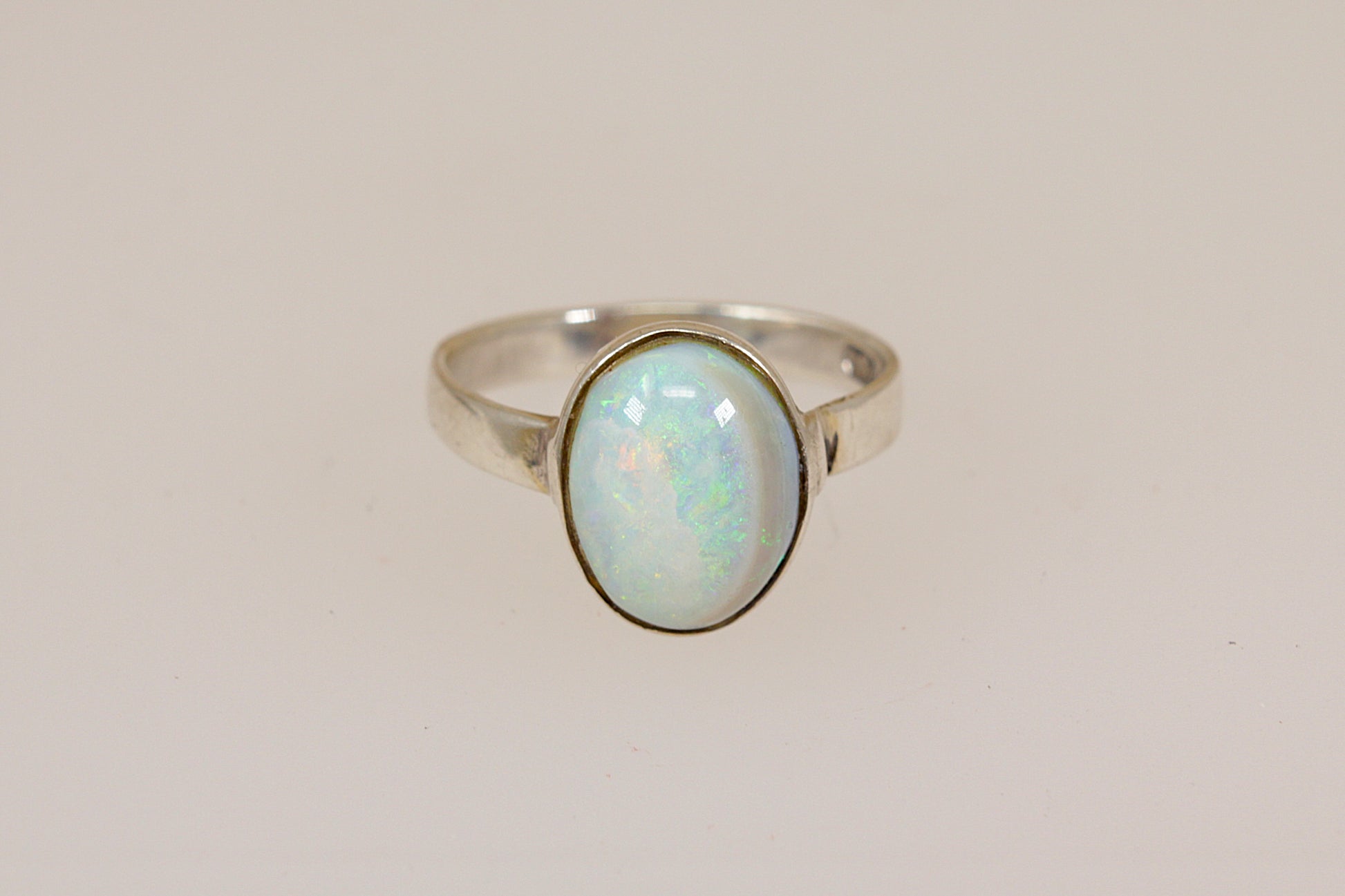 Silver ring with an opal stone on a light beige background