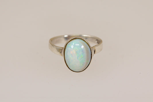 Silver ring with an opal stone on a light beige background