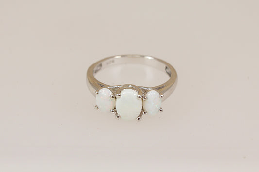 Silver ring with three opal gemstones on a beige background
