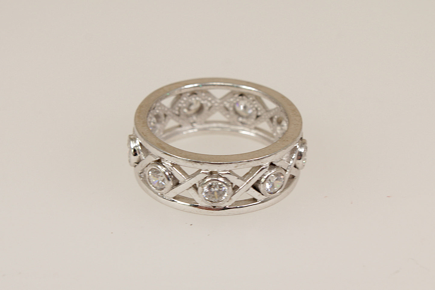 Silver eternity ring with cubic zirconia diamond simulant accents on a light gray background