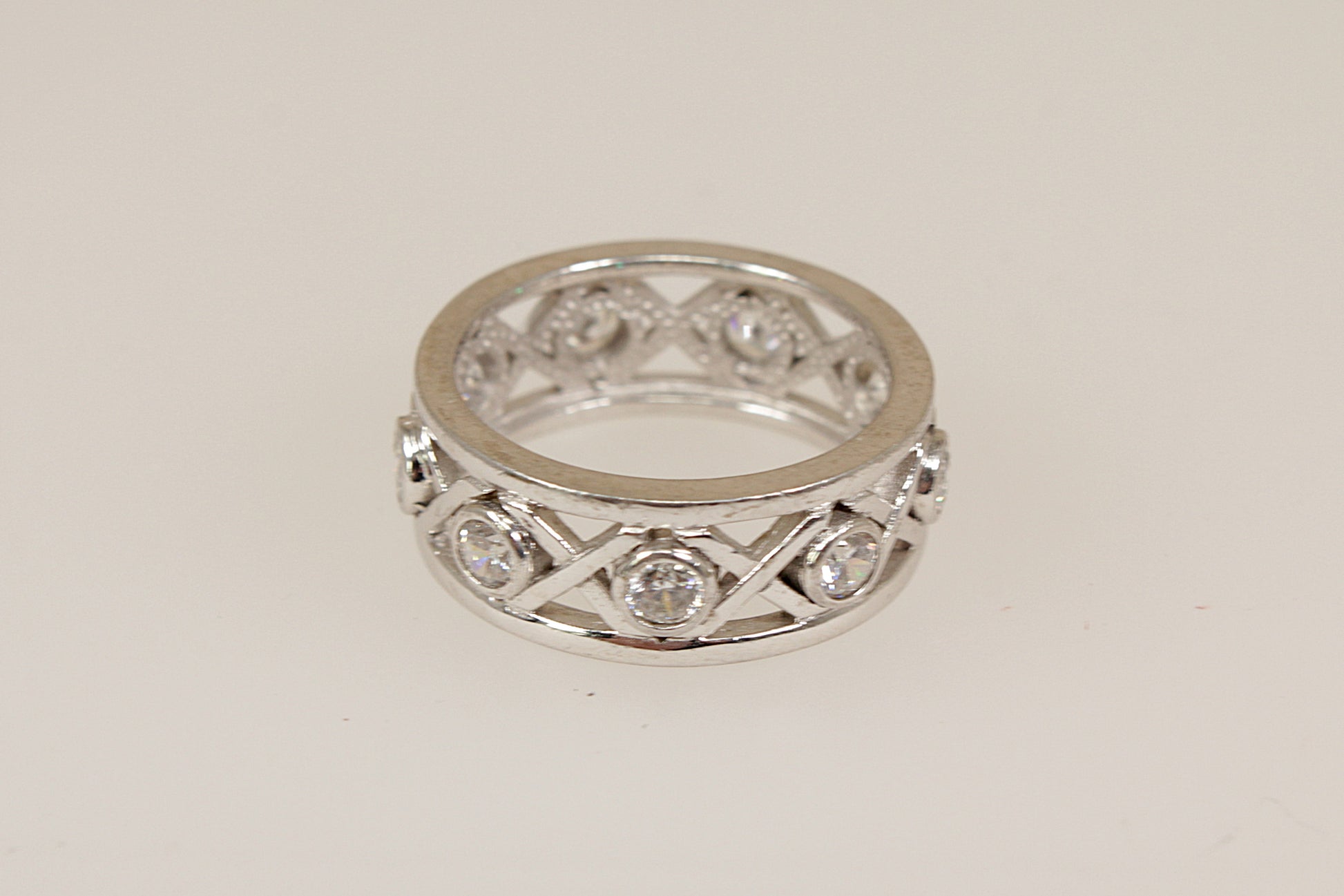 Silver eternity ring with cubic zirconia diamond simulant accents on a light gray background