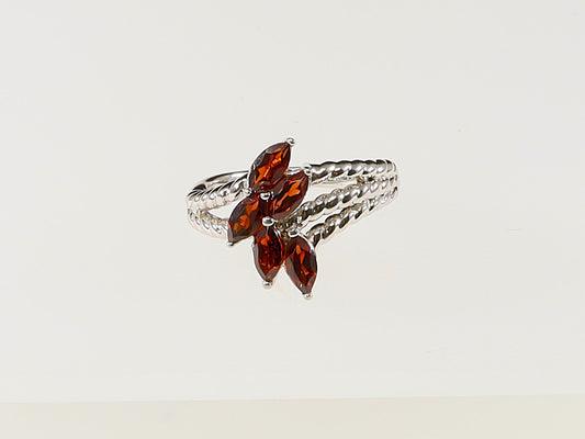 A silver ring with five garnet-colored crystals arranged in a flower pattern.