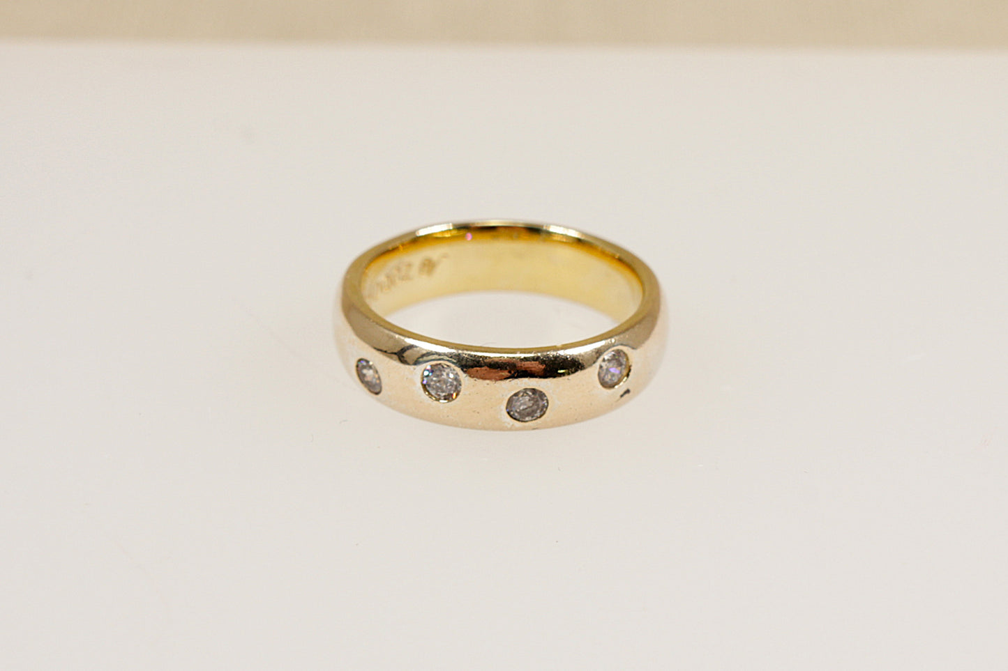 A silver band ring with four round cut cubic zirconia gemstones set flush into the band.