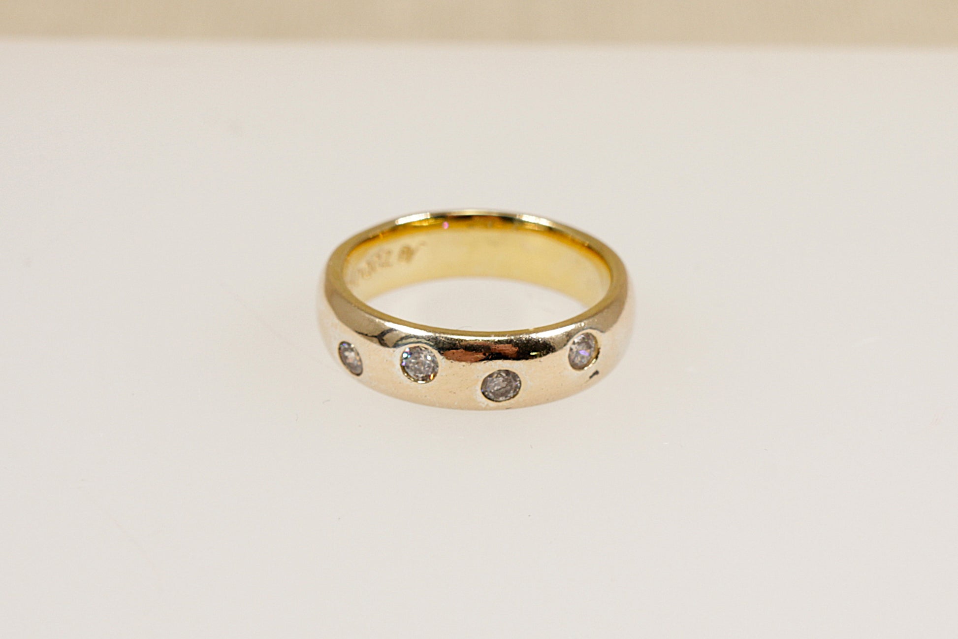 A silver band ring with four round cut cubic zirconia gemstones set flush into the band.