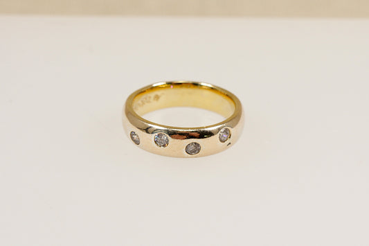 A silver band ring with four round cut cubic zirconia gemstones set flush into the band.