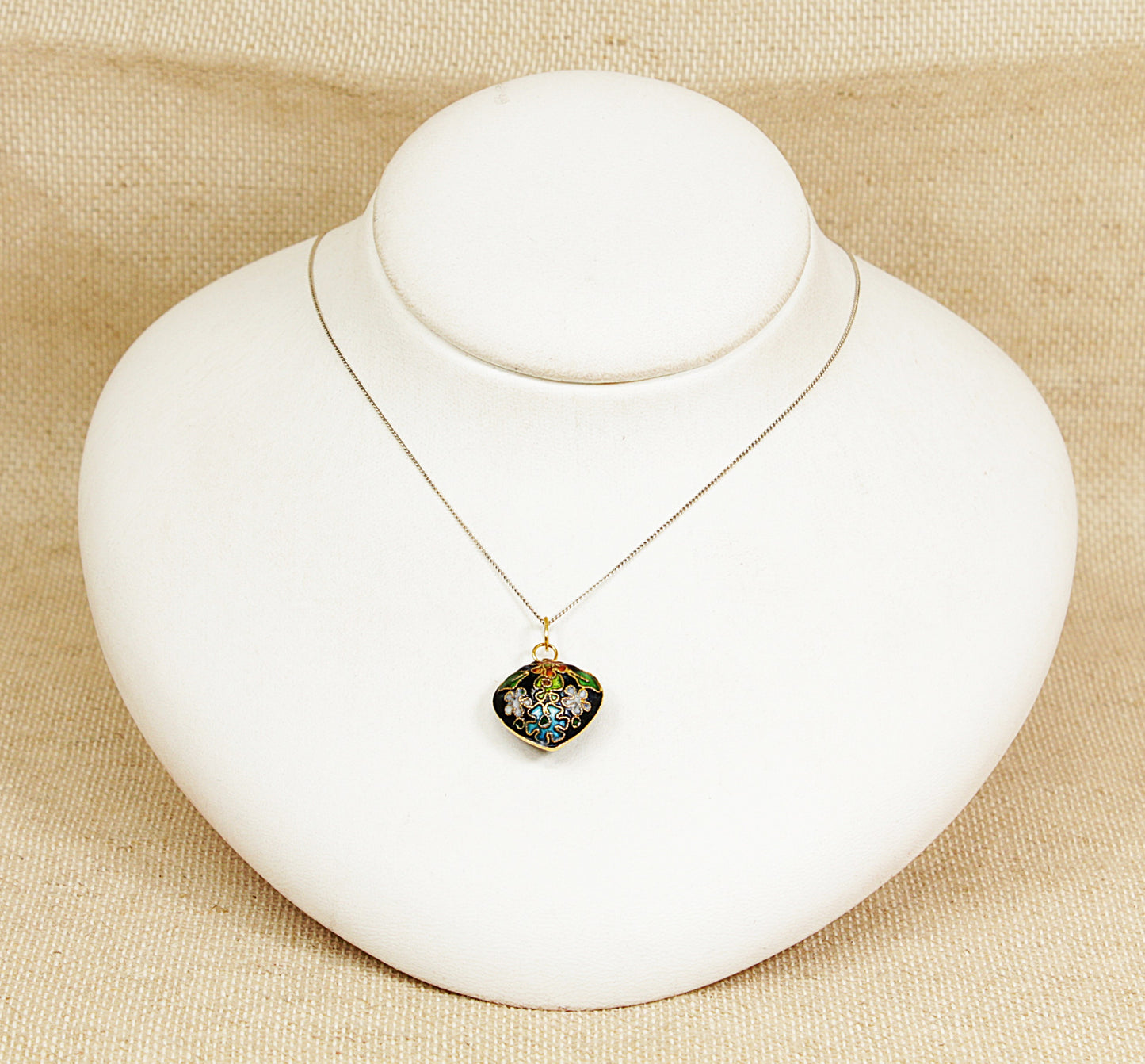Necklace with a heart-shaped pendant on a white mannequin bust against a beige background
