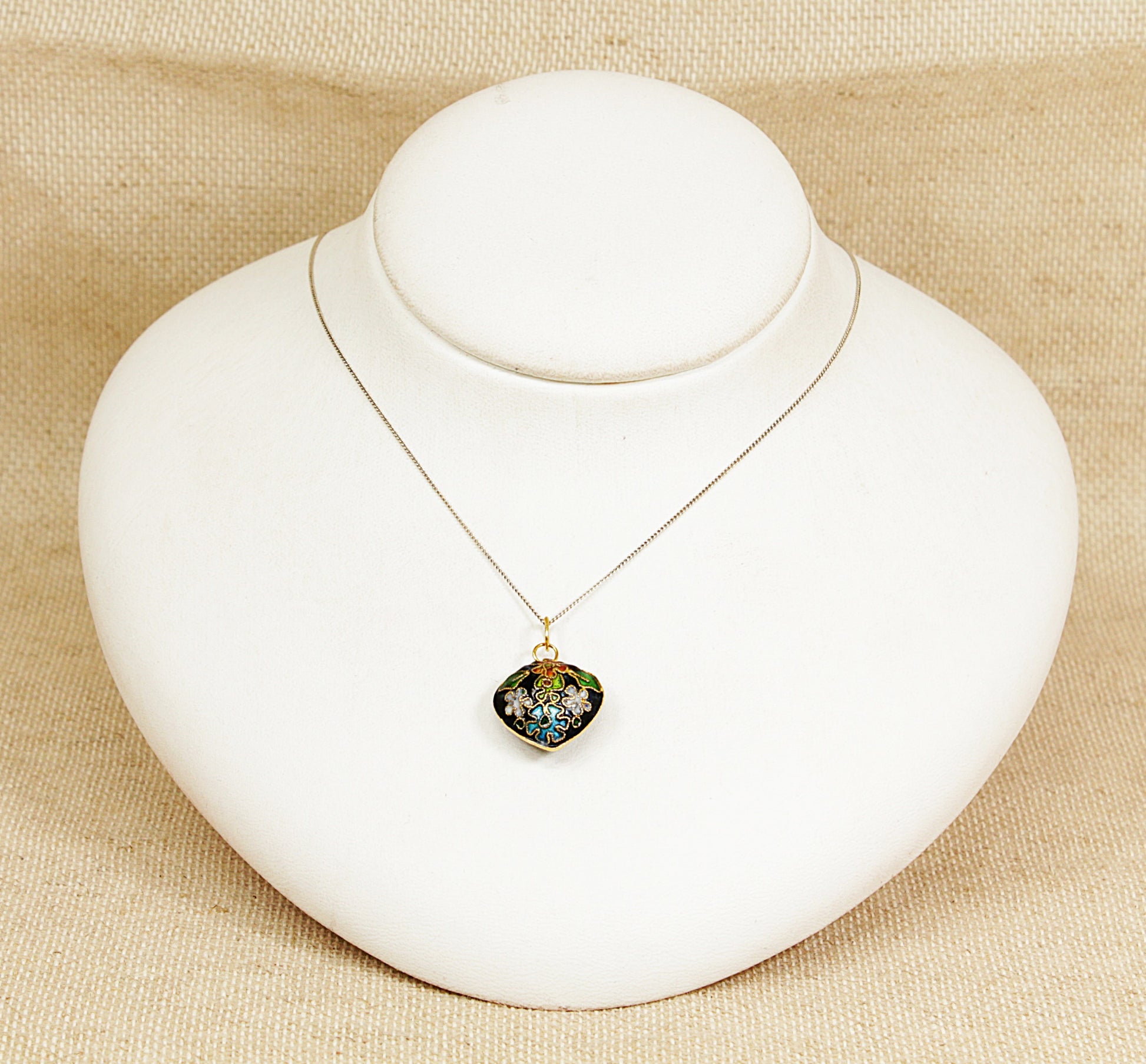 Necklace with a heart-shaped pendant on a white mannequin bust against a beige background