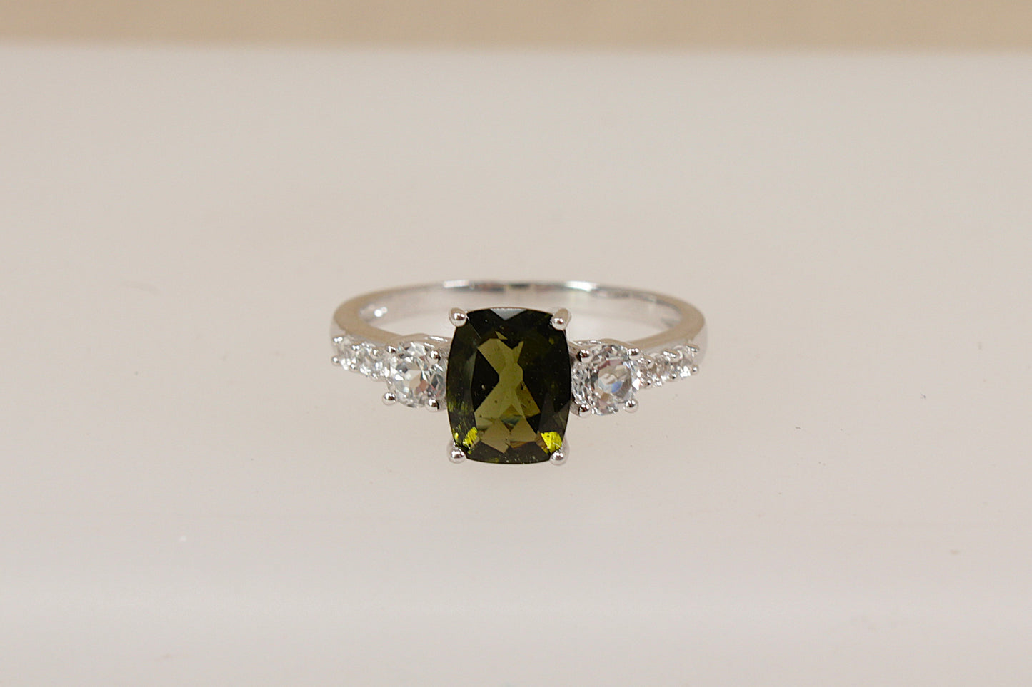 Silver Ring with a green amethyst  gemstone and white topaz accents on a beige background