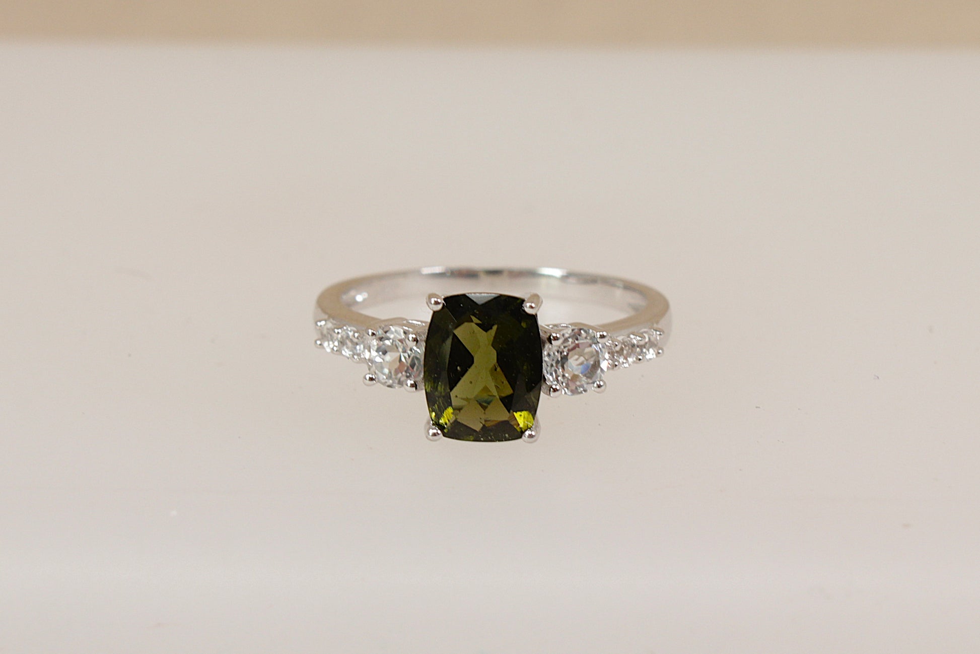 Silver Ring with a green amethyst  gemstone and white topaz accents on a beige background