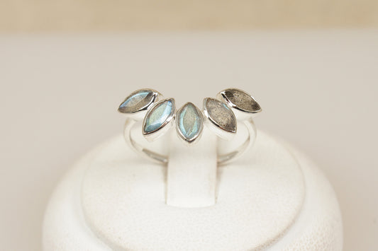 Silver ring with a half halo of labradorite gemstones on a white stand