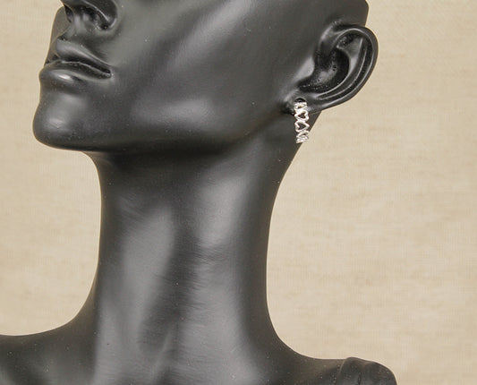 Mannequin head wearing a silver earring against a beige background