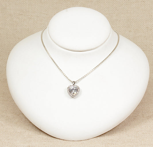 This pretty Silver heart shaped pendant has a large heart shape Cubic Zirconia gemstone set in an ornate basket setting. Around the large CZ heart are smaller CZ stones to give even more sparkle to the pendant. It is in excellent condition, the pendant sits on a 15 inch silver box chain. It is stamped 925 for sterling silver.
