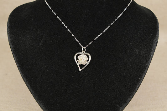 Necklace with a heart-shaped pendant featuring a rose on a black velvet stand.