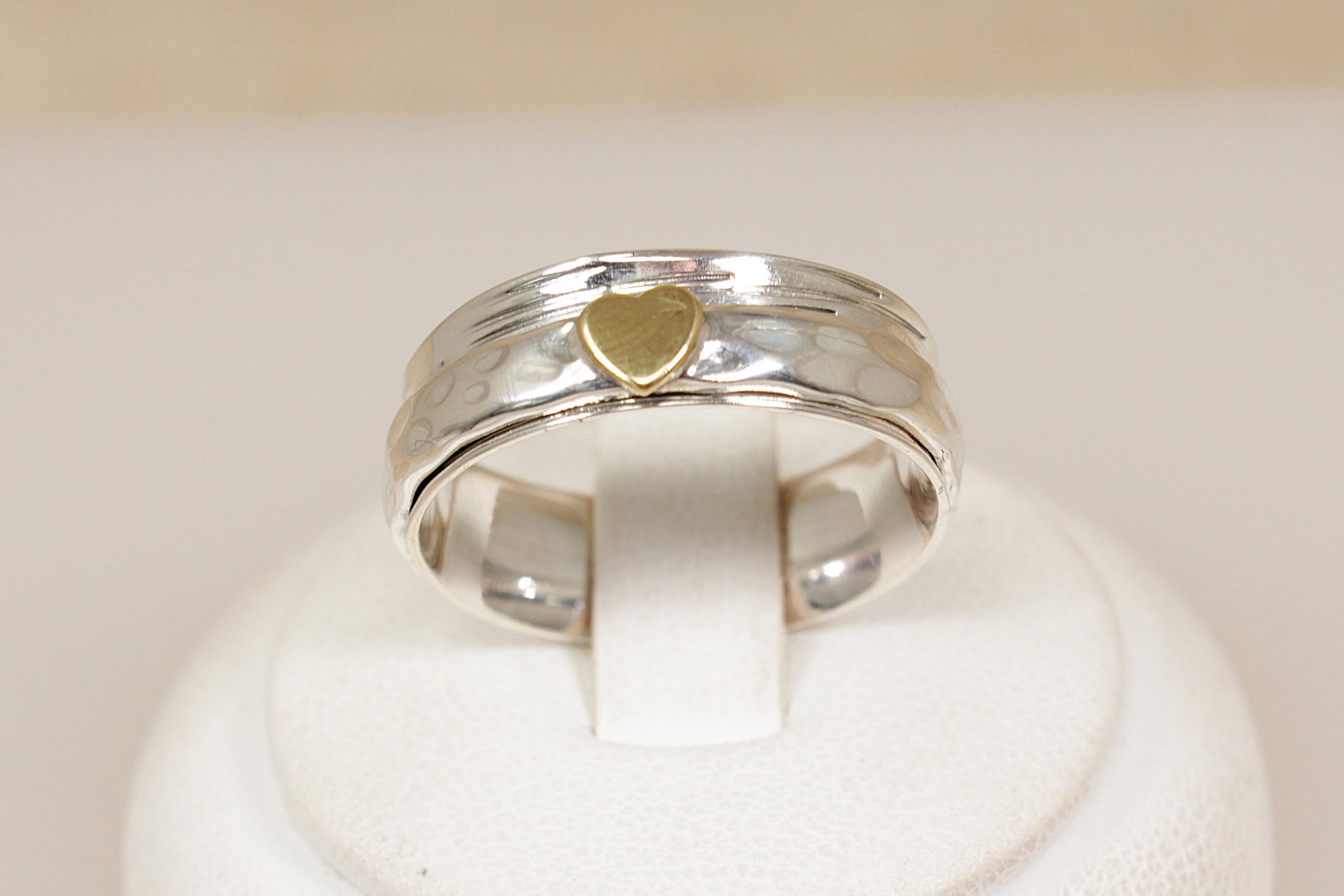 Silver ring with a gold heart-shaped inset on a white background