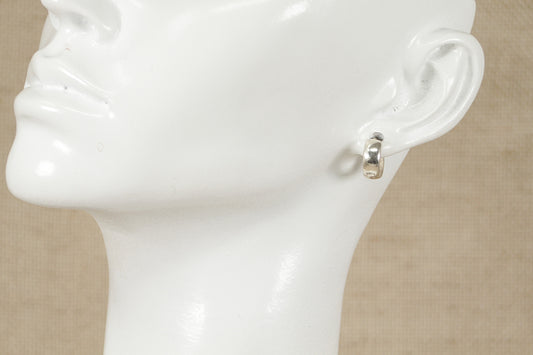 A pair of silver hoop earrings displayed on a mannequin head.
