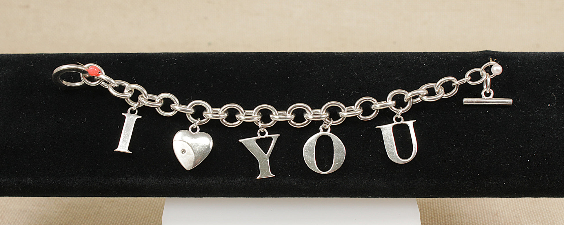 Silver bracelet with 'I LOVE YOU' charms on a black stand