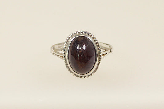 A silver ring with a large cabochon iolite gemstone, showcasing an oval shape with a deep indigo color, set in a handcrafted band with hallmarks for 1991.