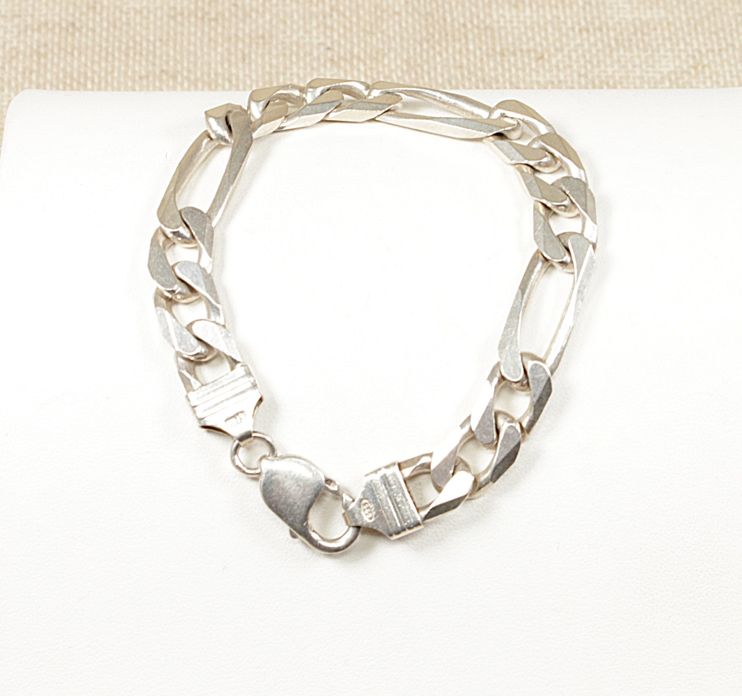A silver Italian Figaro bracelet with a robust lobster clasp, displayed on a white surface.