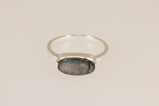 Silver ring with a labradorite stone on a beige background