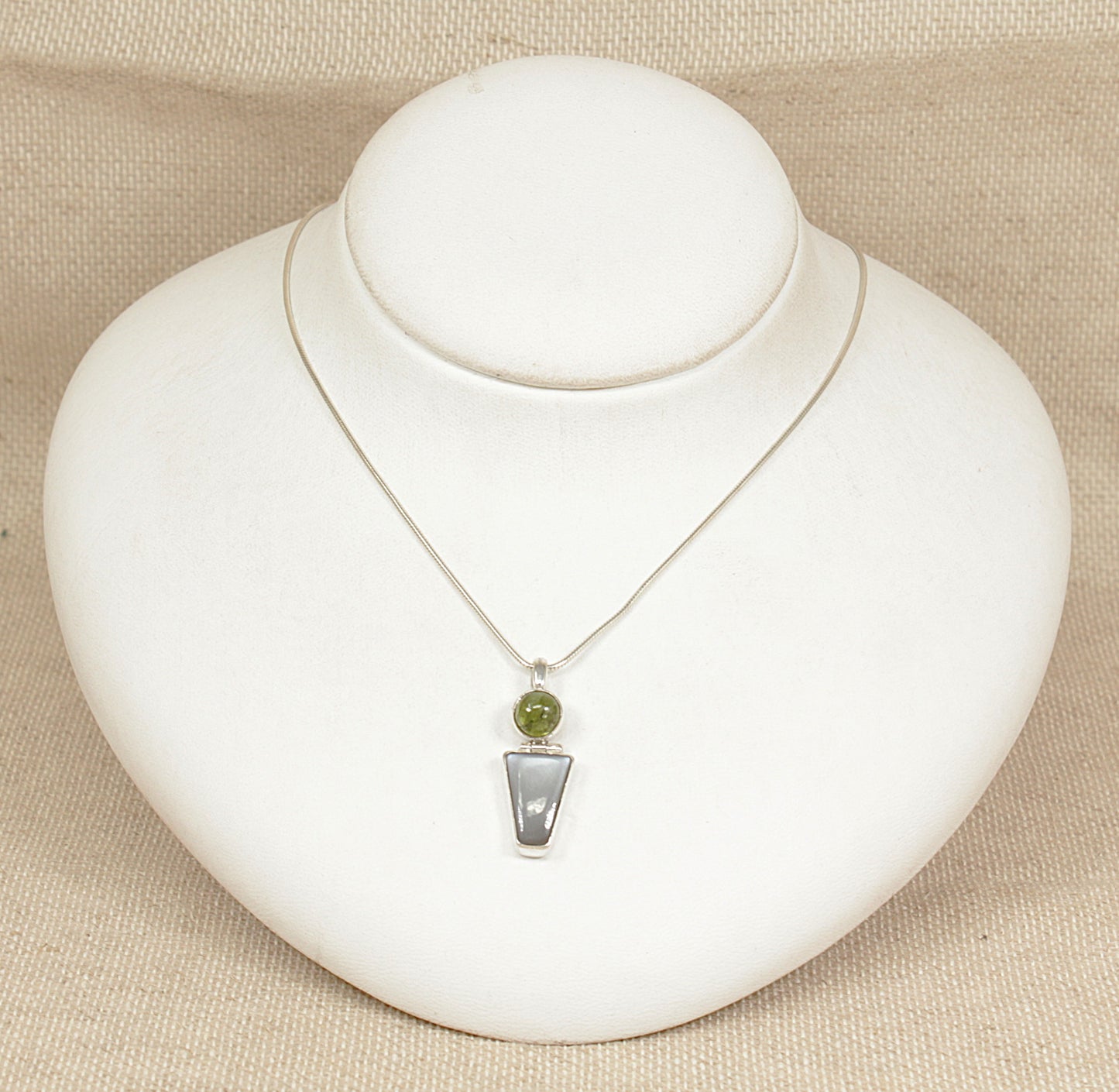 Necklace with a pendant on a white mannequin bust against a beige background