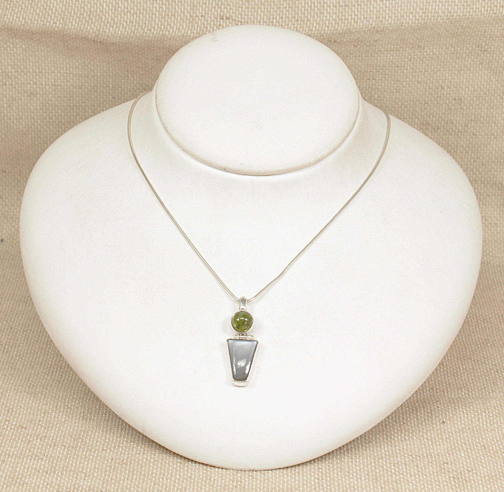 Necklace with a pendant on a white mannequin bust against a beige background