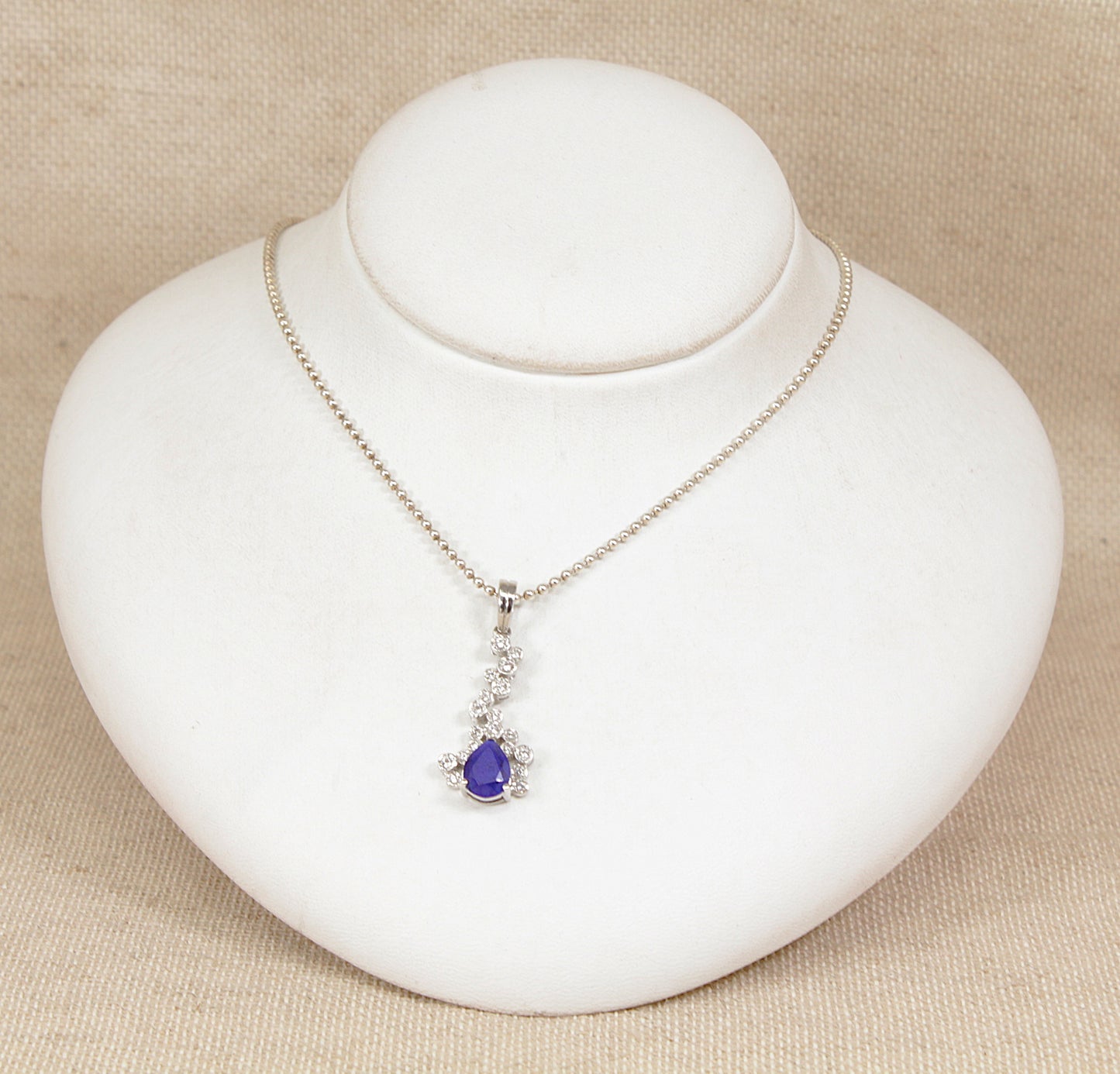Necklace with a purple lapis lazuli pendant on a white jewelry display