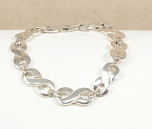 Sterling Silver bracelet with figure of eight links on a white surface with a beige background.