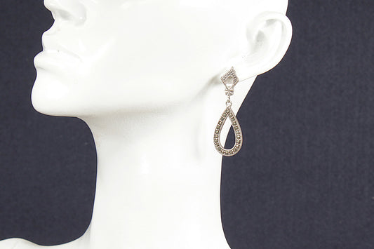 Teardrop-shaped vintage marcasite earring on a white mannequin ear against a dark background