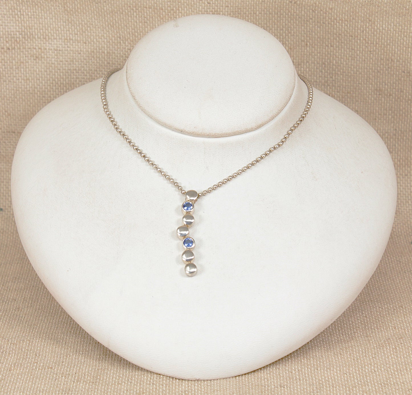 Necklace with a pendant on a white mannequin bust against a beige background