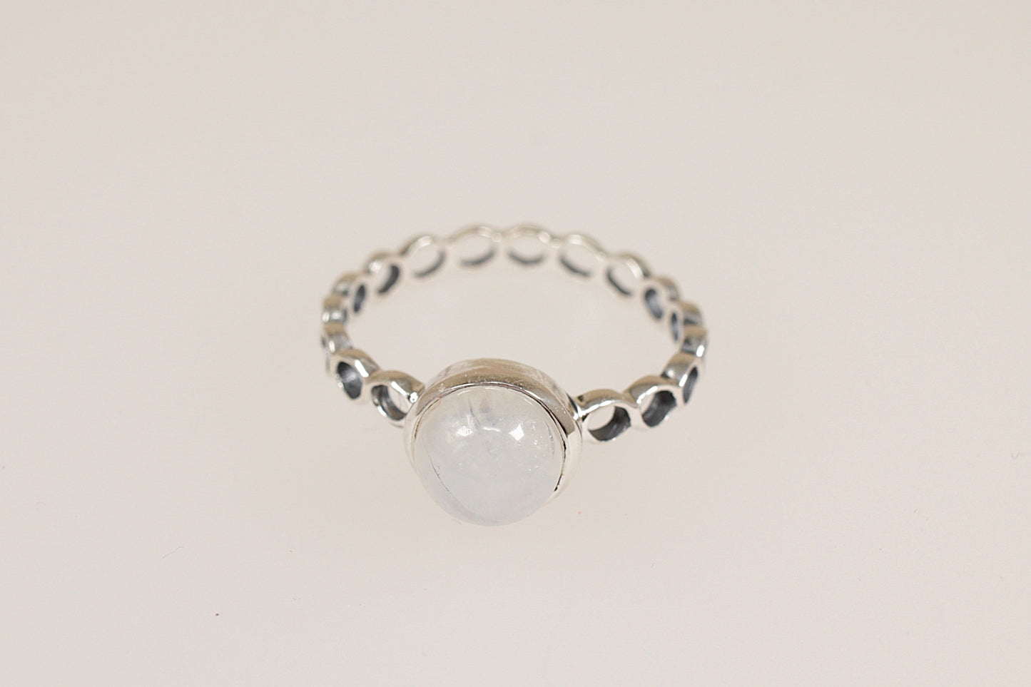 Silver ring with a round moonstone gemstone on a light beige background