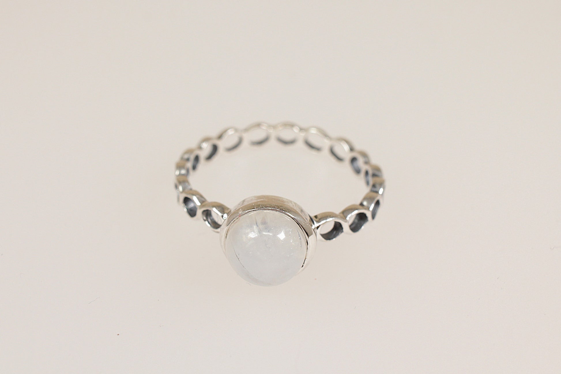 Silver ring with a round moonstone gemstone on a light beige background