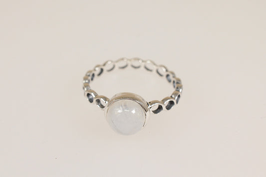 Silver ring with a round moonstone gemstone on a light beige background
