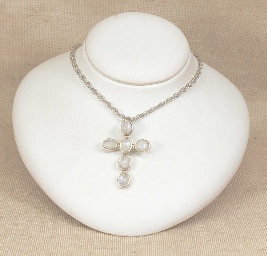 Silver cross necklace with moonstone  on a white mannequin bust against a beige background