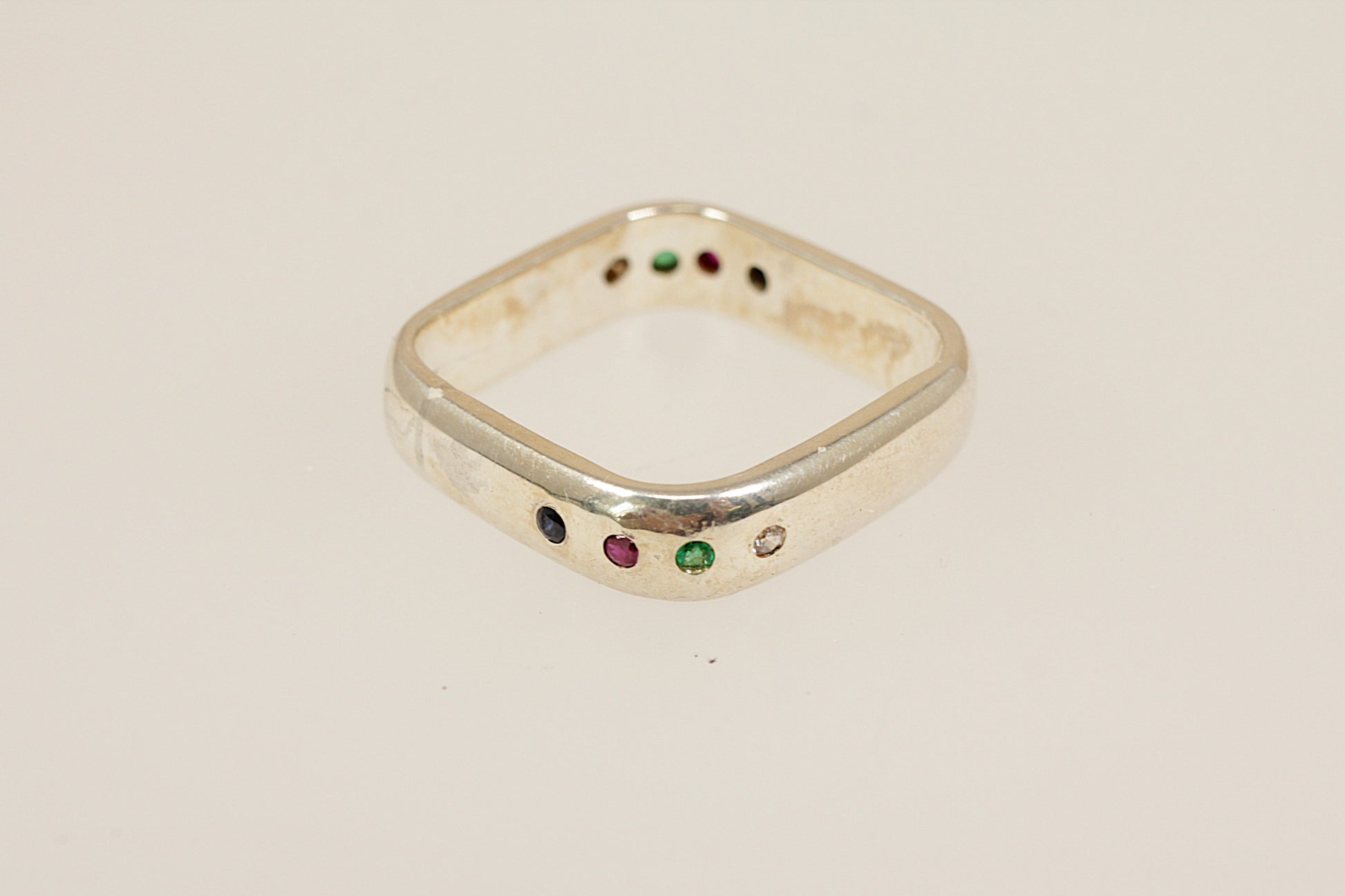 Sterling silver ring with colored gemstones on a beige background