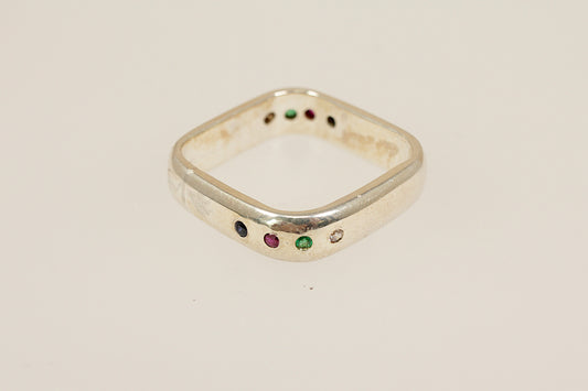 Sterling silver ring with colored gemstones on a beige background