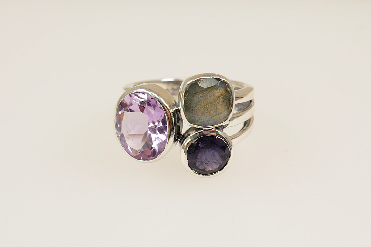 This stunning new Silver ring features 3 large faceted gemstones, Amethyst, Blue Iolite and Labradorite. Set in a stylish and contemporary split band design, it is a bold and artistic statement piece. UK finger size O.