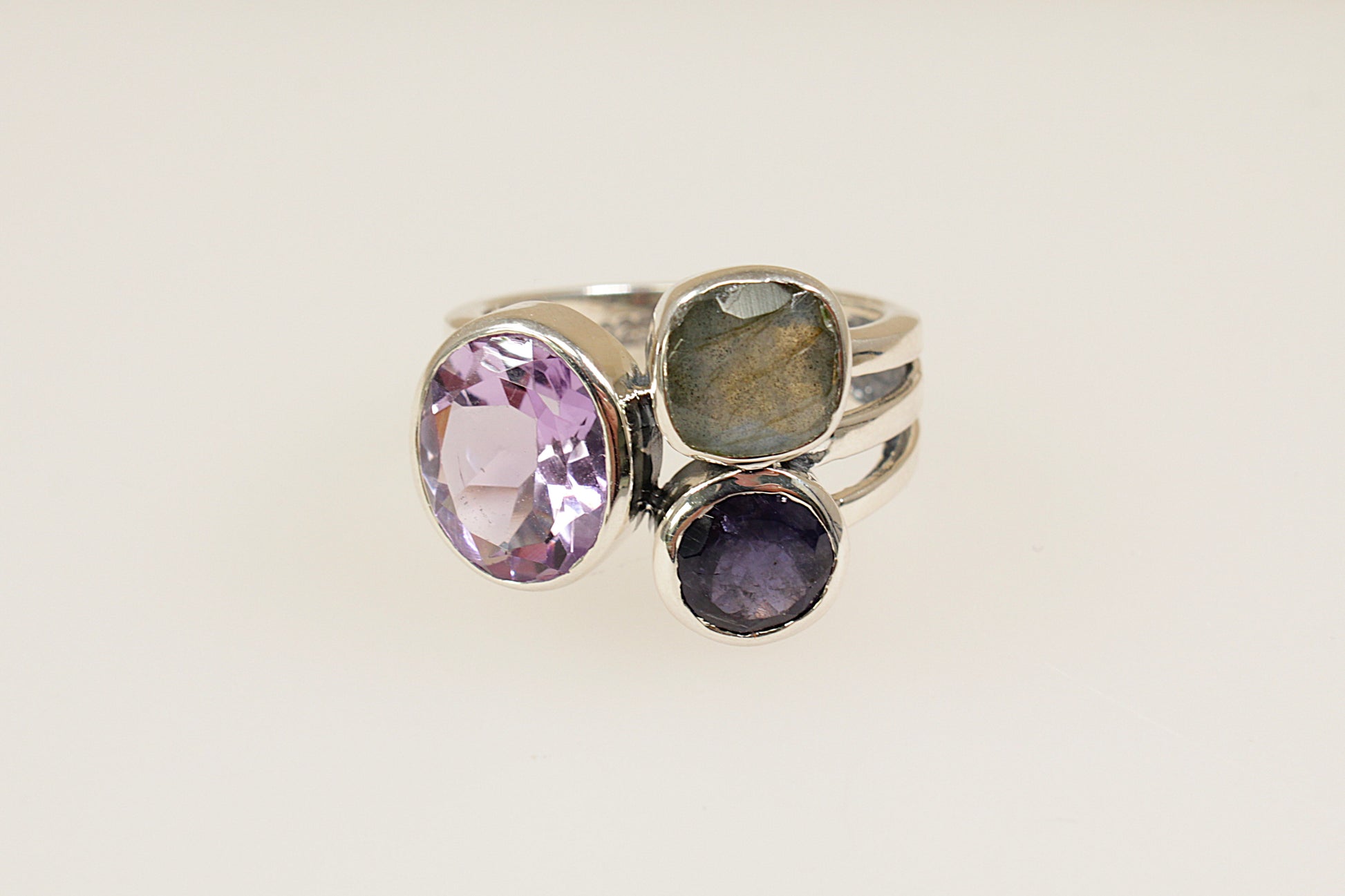 This stunning new Silver ring features 3 large faceted gemstones, Amethyst, Blue Iolite and Labradorite. Set in a stylish and contemporary split band design, it is a bold and artistic statement piece. UK finger size O.