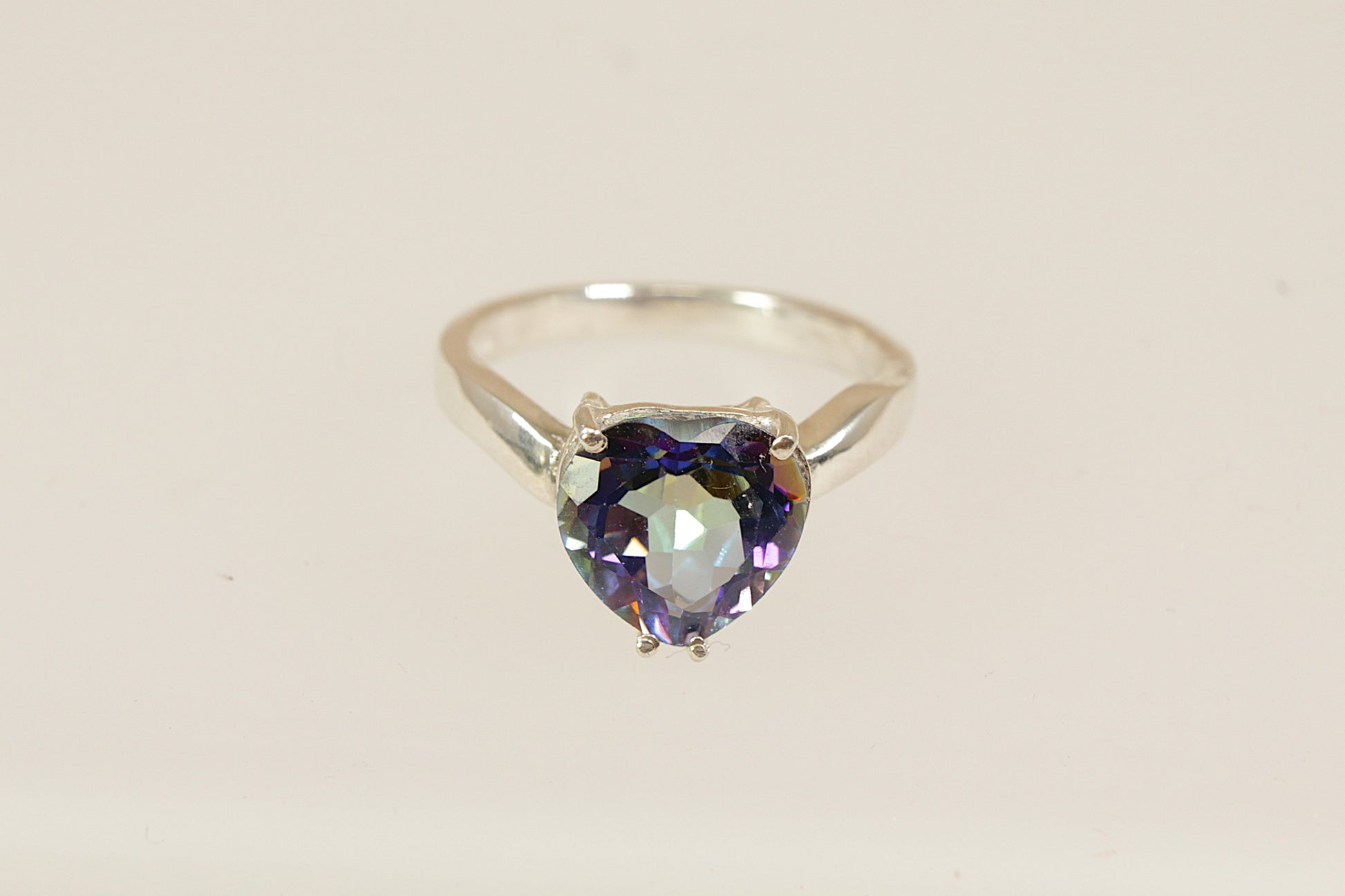A lovely and eye-catching sterling silver statement ring featuring a dazzling heart-shaped mystic blue topaz as the centrepiece. The stone shimmers with enchanting iridescent tones, ranging from deep blue to flashes of green and violet, depending on the light. UK finger sie P.