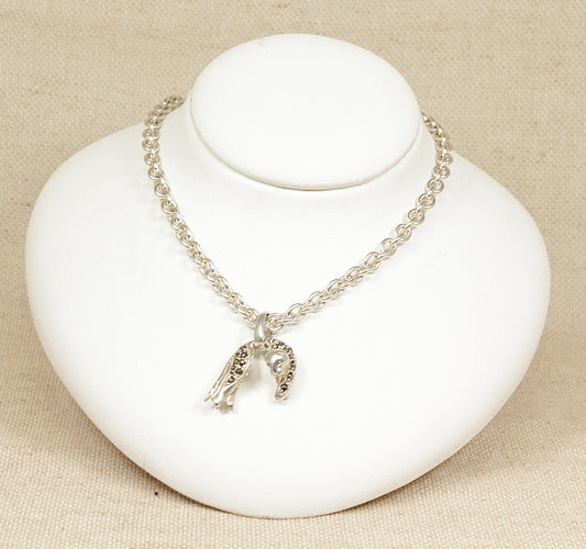 A silver necklace with a leopard pendant and two heart charms displayed on a white mannequin.