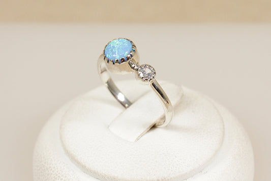 Silver ring with a blue opal gemstone on a white background