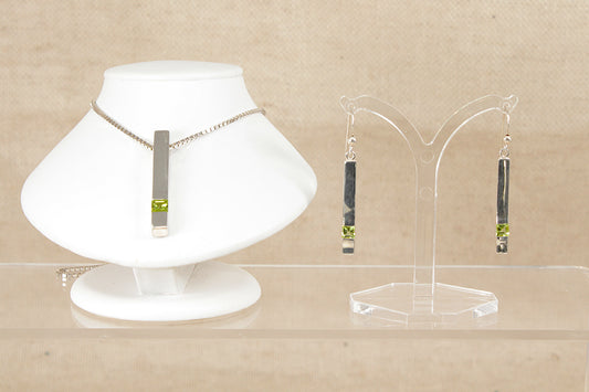 Jewelry set with peridot set gemstone necklace and earrings on a beige background