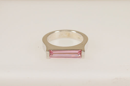 A silver ring with a horizontal pink crystal centerpiece, set on a white background.